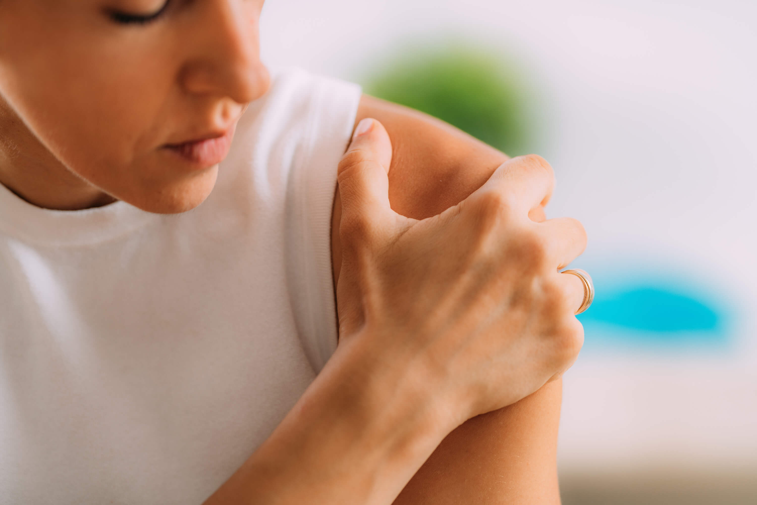 Woman looking down at her shoulder and holding it with her hand